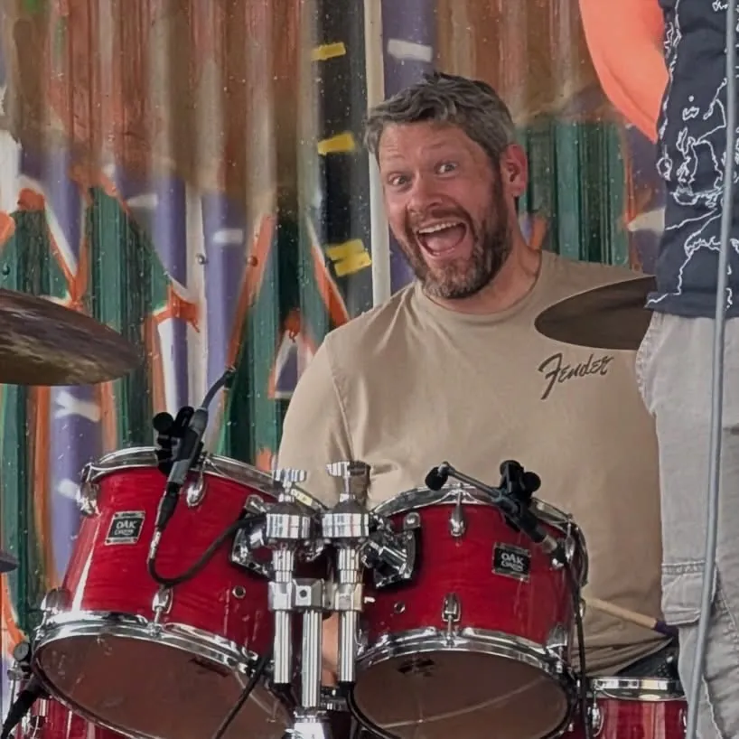 Brad grinning behind a red drum kit