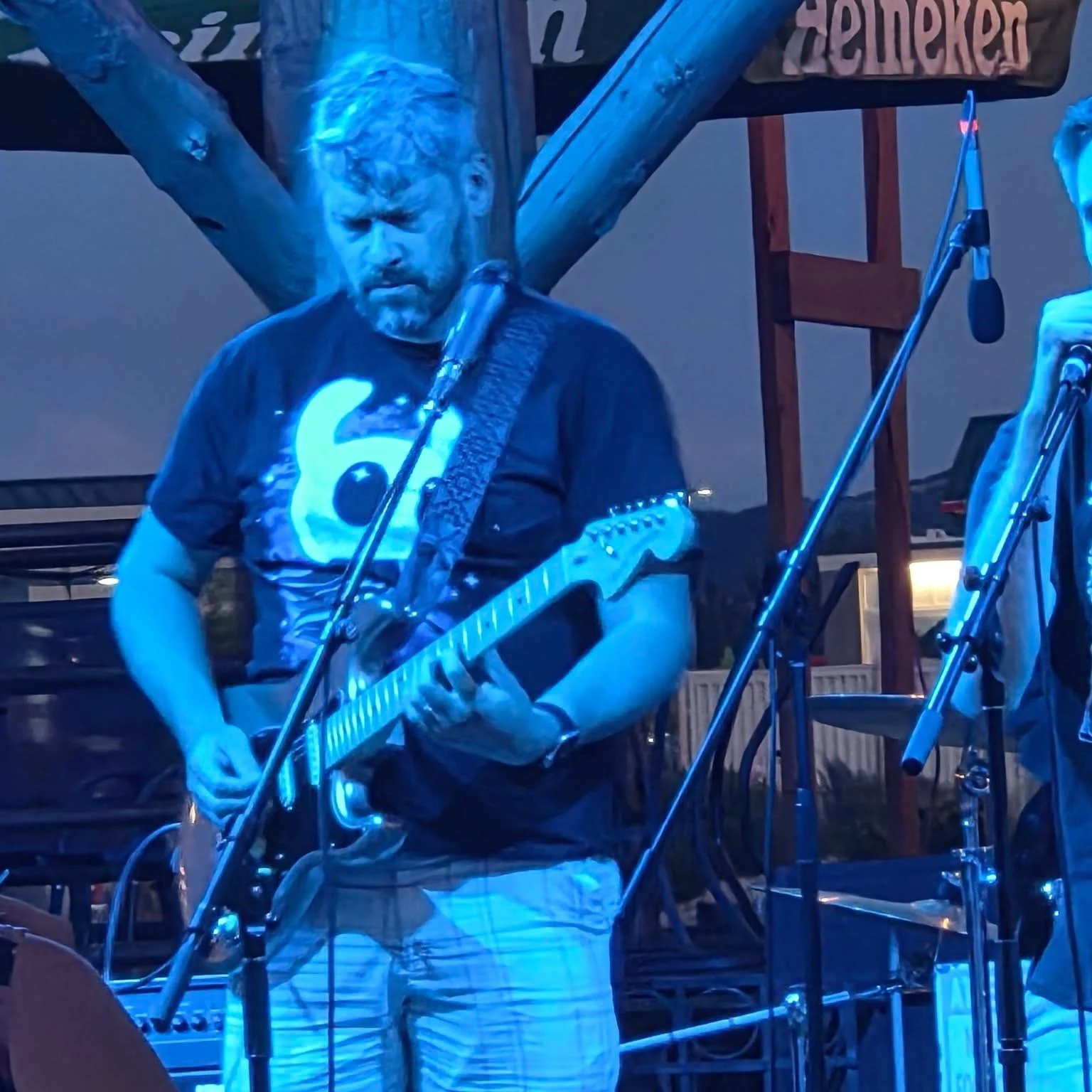 Brad playing electric guitar under blue stage lights